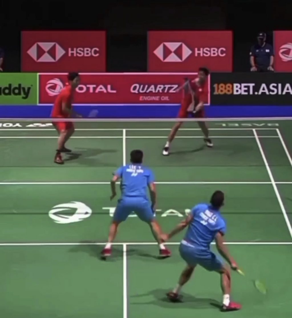 Badminton match played on court while a player dives